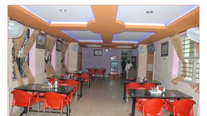 Comedor con mesas, sillas, ventiladores de techo y una máquina expendedora.