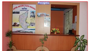 Un mostrador de recepción con un mapa y un cartel de atracciones locales, plantas en macetas y una decoración floral.
