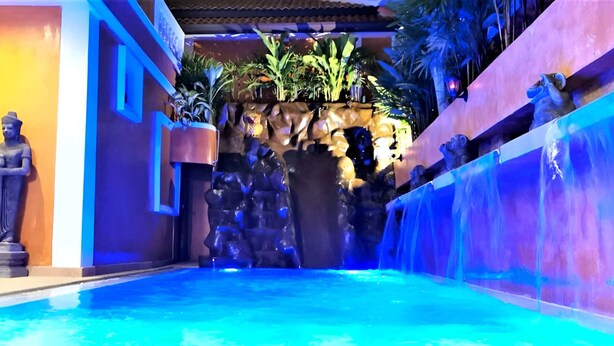 A pool area with a waterfall, statues, and tropical plants. - HIDELAND Luxury Pool Villa Pattaya Walking Street (Pattaya)