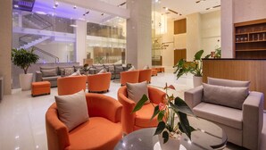 A modern lobby with orange and grey sofas, a staircase, and a reception desk. - King Town Grand Hotel & Wedding Center (Bac Nha Trang)