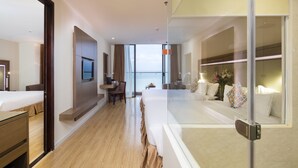 A modern hotel room with a bed, desk, and seating area, featuring a large window with a view of the sea. - King Town Grand Hotel & Wedding Center (Bac Nha Trang)