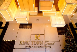 Letrero del King Town Grand Hotel & Wedding Center con un moderno elemento decorativo luminoso geométrico arriba.
