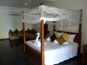 A four-poster bed with a canopy, a sofa with cushions, and a wooden nightstand. - Beach Villa Lanka (Tangalle)