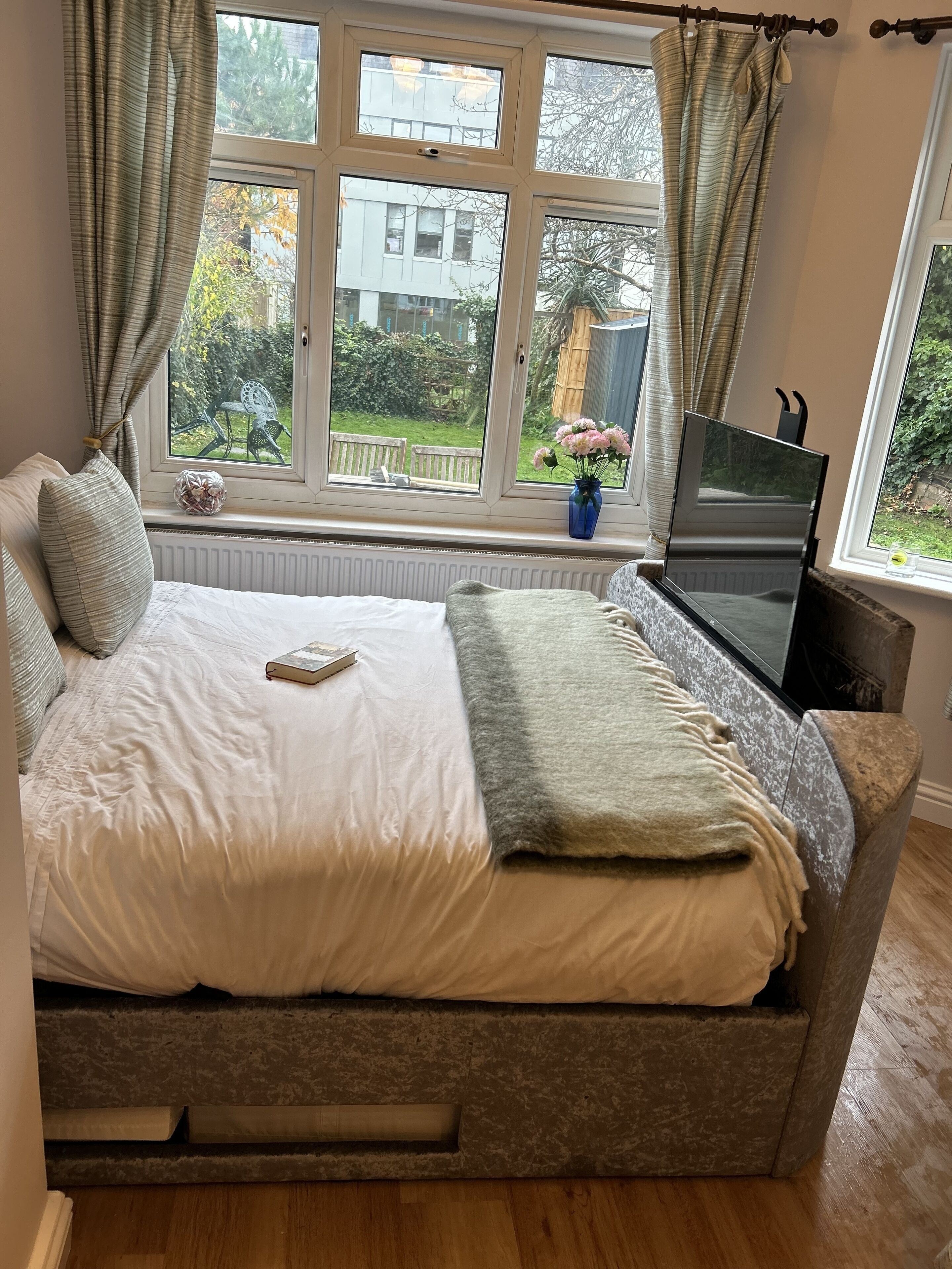 A bedroom with a bed, a TV, and a window with curtains.