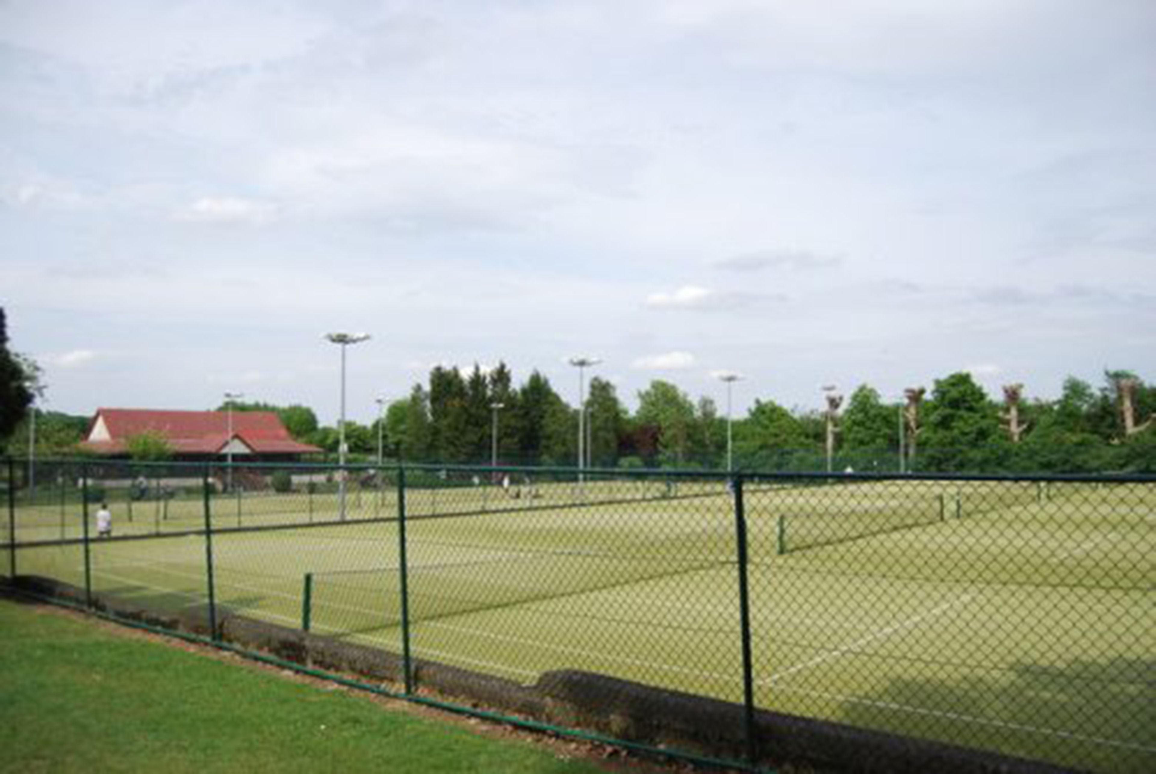 A fenced tennis court with a building in the background.
