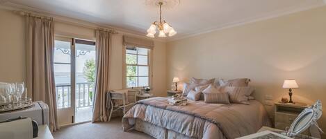 A bedroom with a large bed, two bedside tables with lamps, a dresser, a chair, and a view of the outdoors through a sliding door.