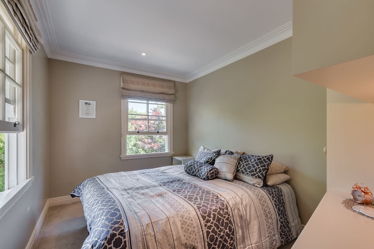 A bedroom with a large bed, a window with a view, and a small bedside table.