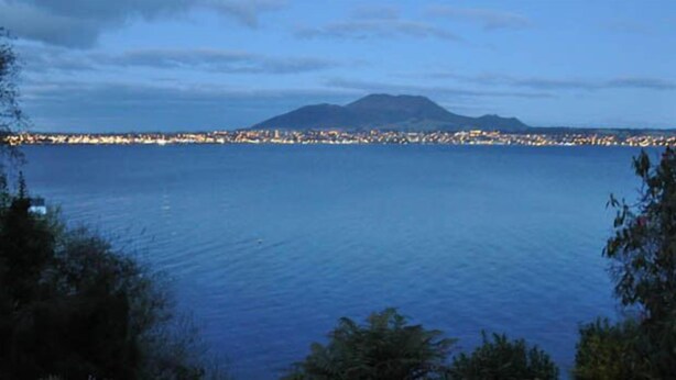 A coastal cityscape with a mountain in the background and a body of water in the foreground. - Belle vue Boutique Lodge (Taupo)