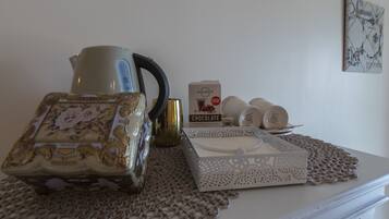 A table with a decorative box, a coffee maker, a chocolate box, and a plate with cups.
