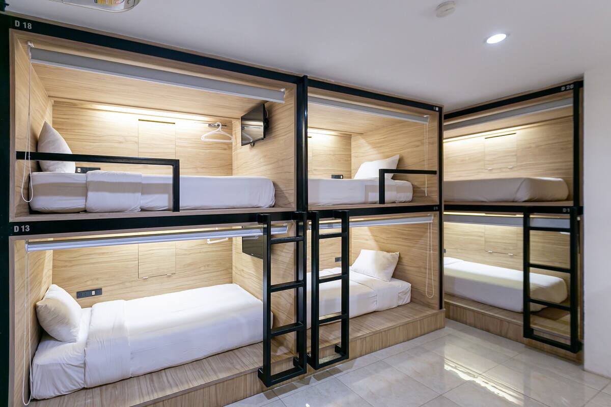 Een slaapkamer met stapelbedden, een houten inrichting, een hanglamp en een spiegel aan de muur.