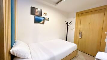 Une chambre à coucher avec un lit, une porte en bois et des tableaux accrochés au mur.