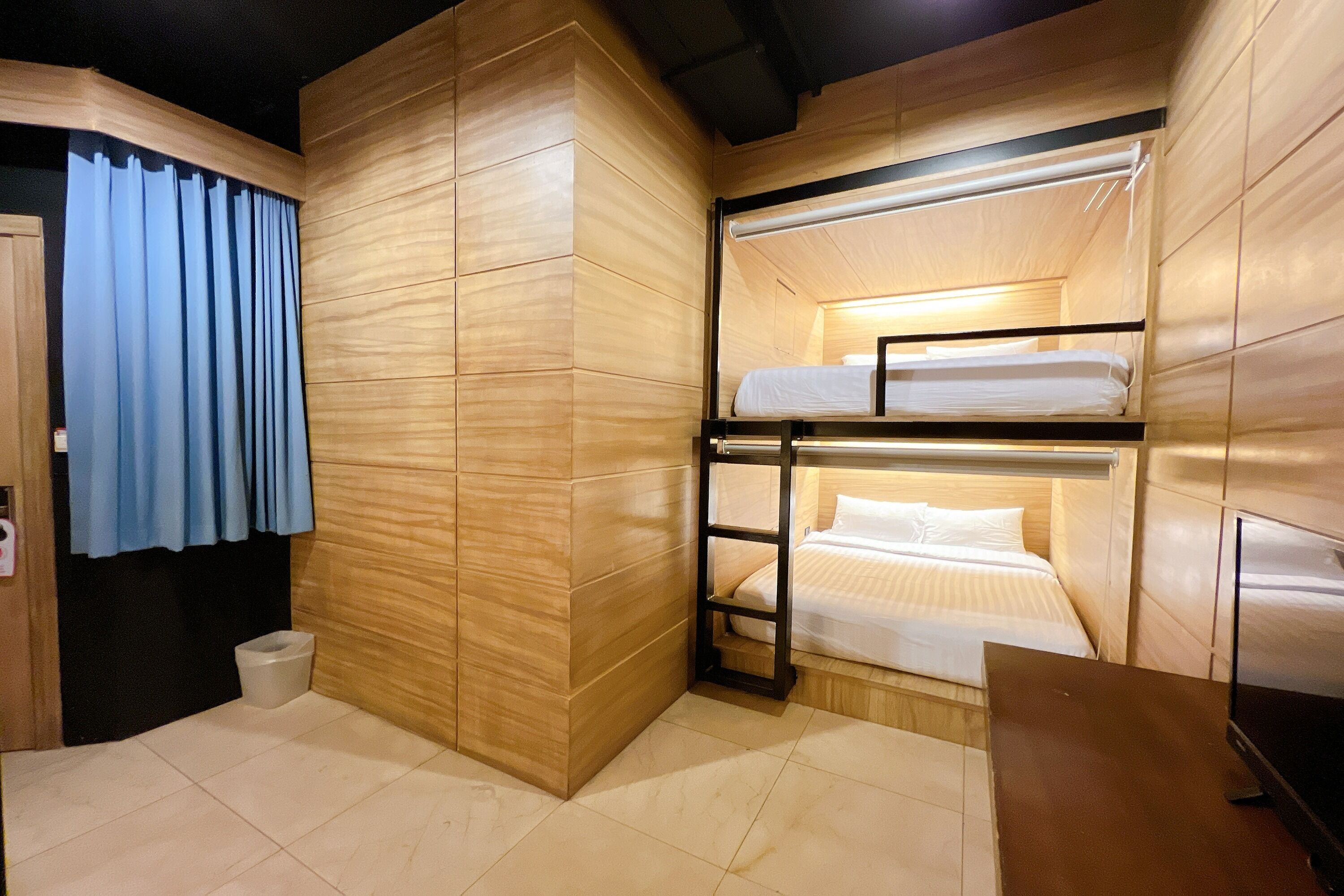 Habitación pequeña con literas, un escritorio y televisión.