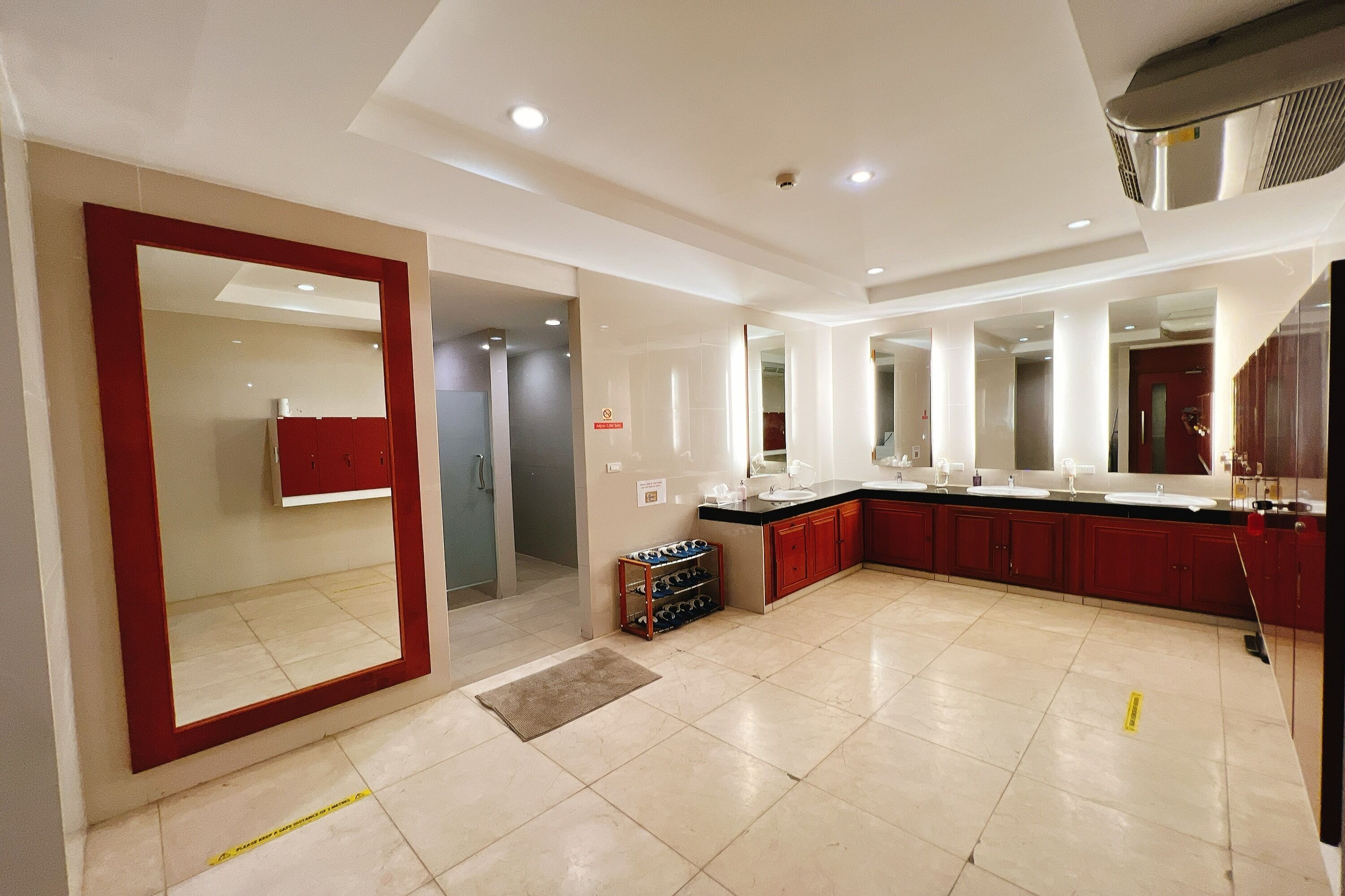 A modern kitchen with a large mirror, red cabinets, and a tiled floor.