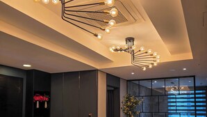 A modern hotel lobby with a marble coffee table, a seating area, and a dining space. - Embledon Hotel (Ansan)