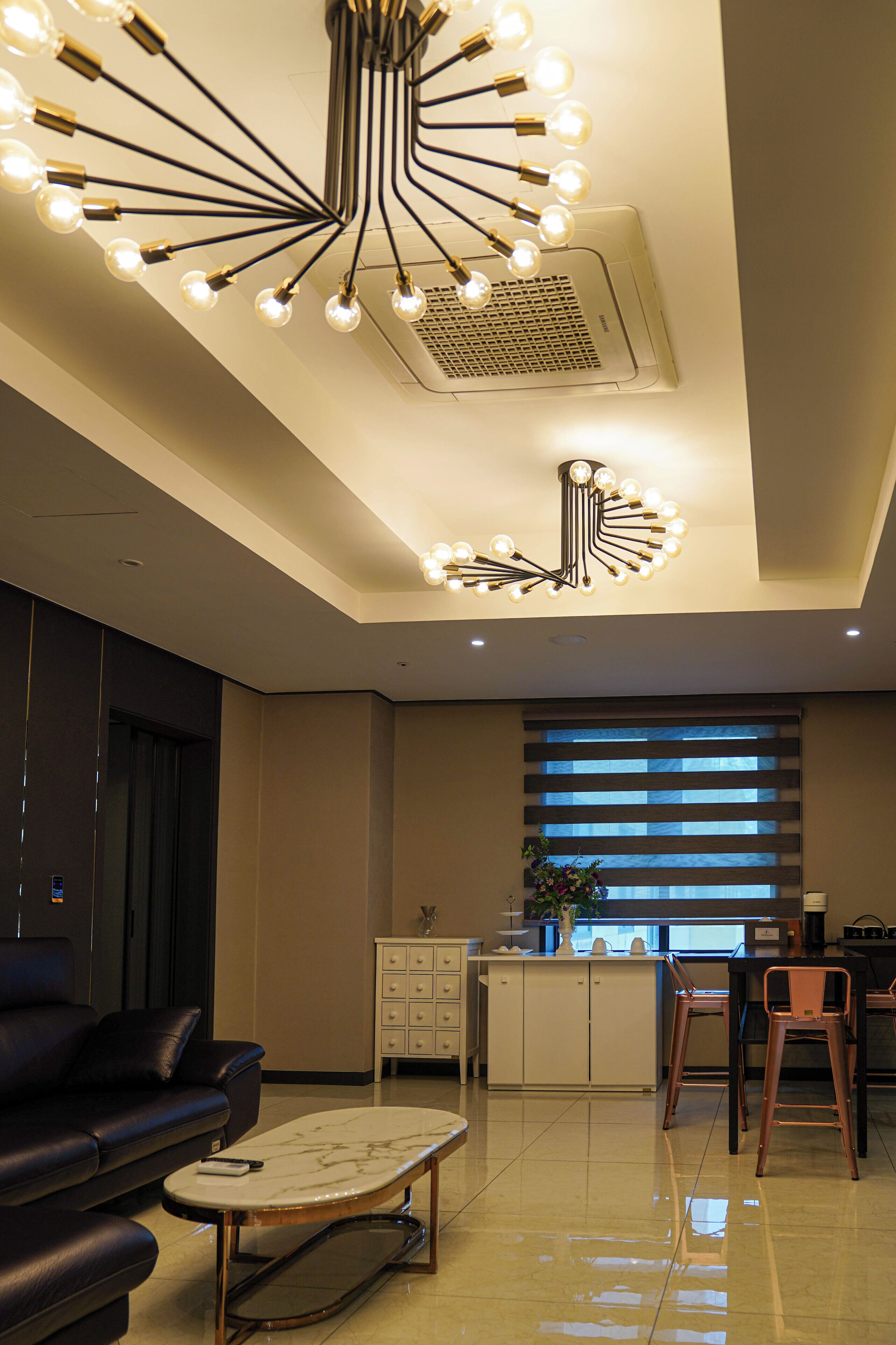 Una sala de estar moderna con sofá, una mesa de centro, un comedor con sillas y una cocina al fondo.