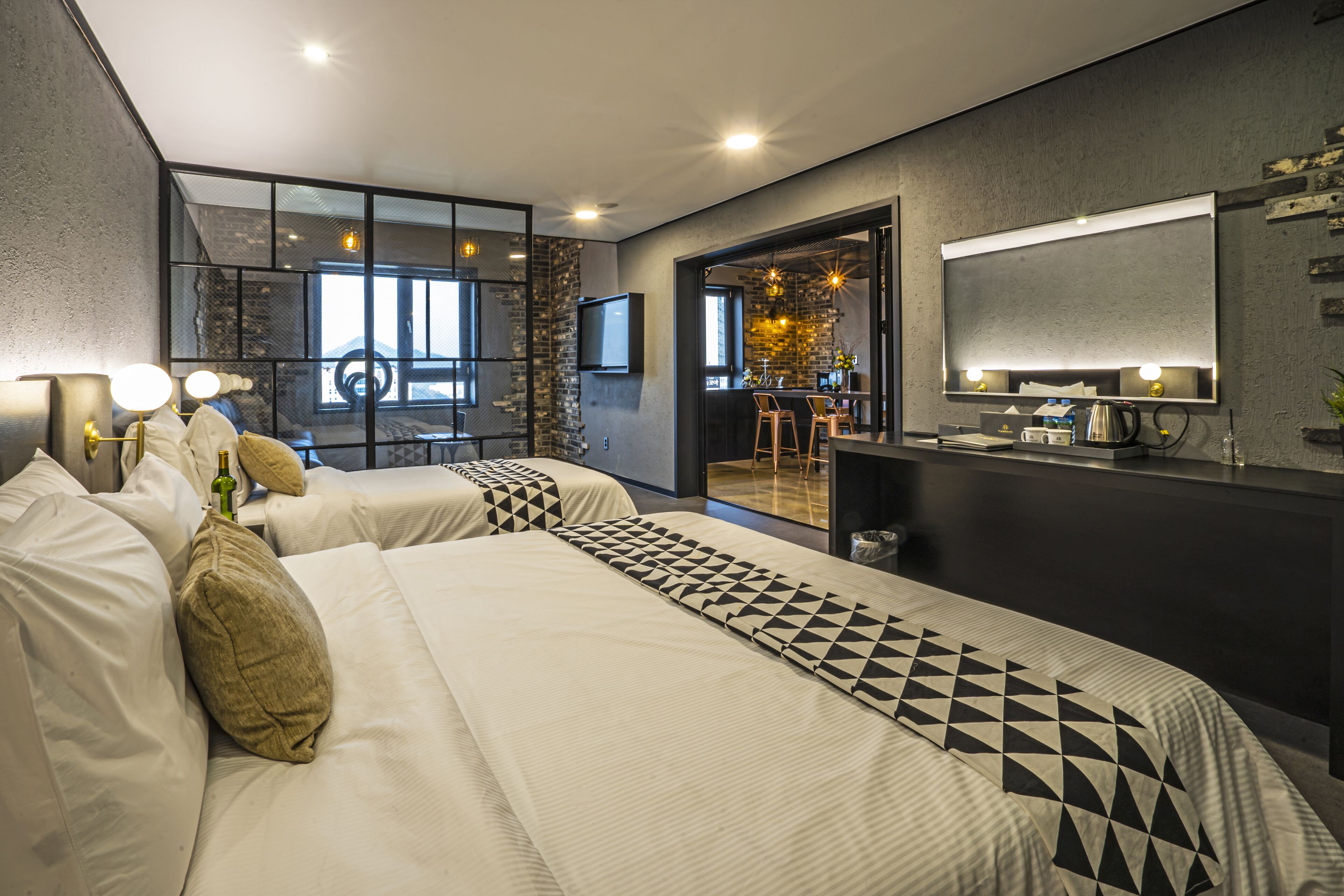 A modern hotel room with a large bed, a desk, and a mirror.