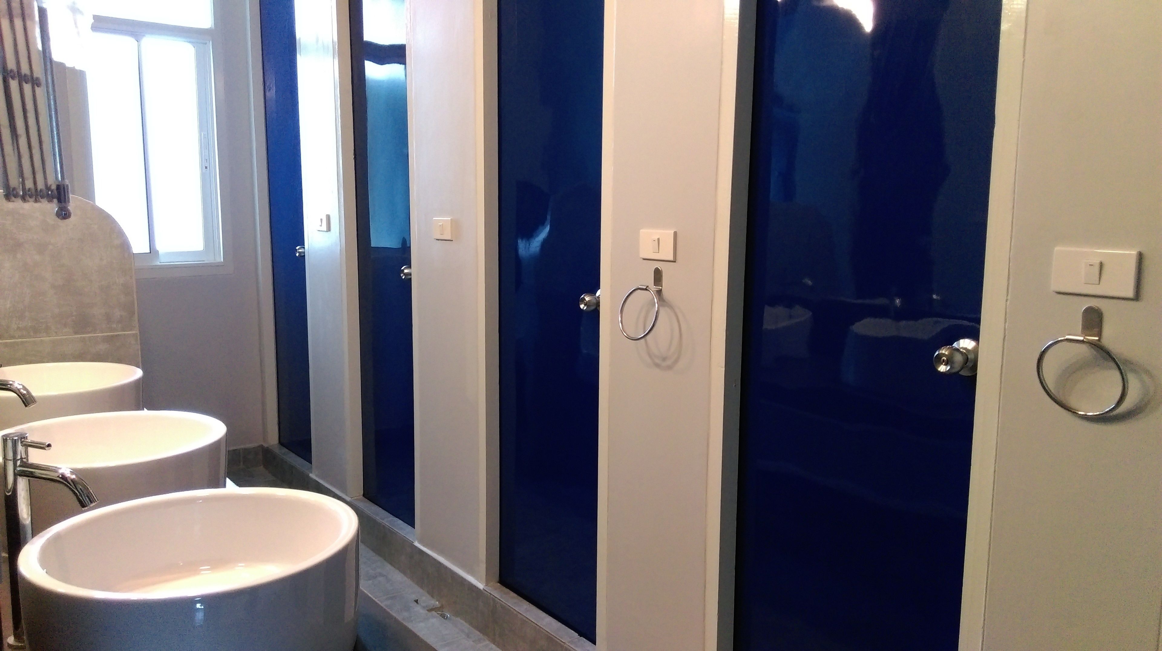 Ein Badezimmer mit drei Waschbecken, einem Spiegel und einer Duschkabine.
