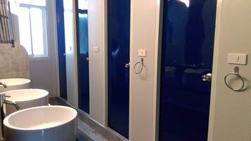 Ein Badezimmer mit drei Waschbecken, einem Spiegel und einer Duschkabine.