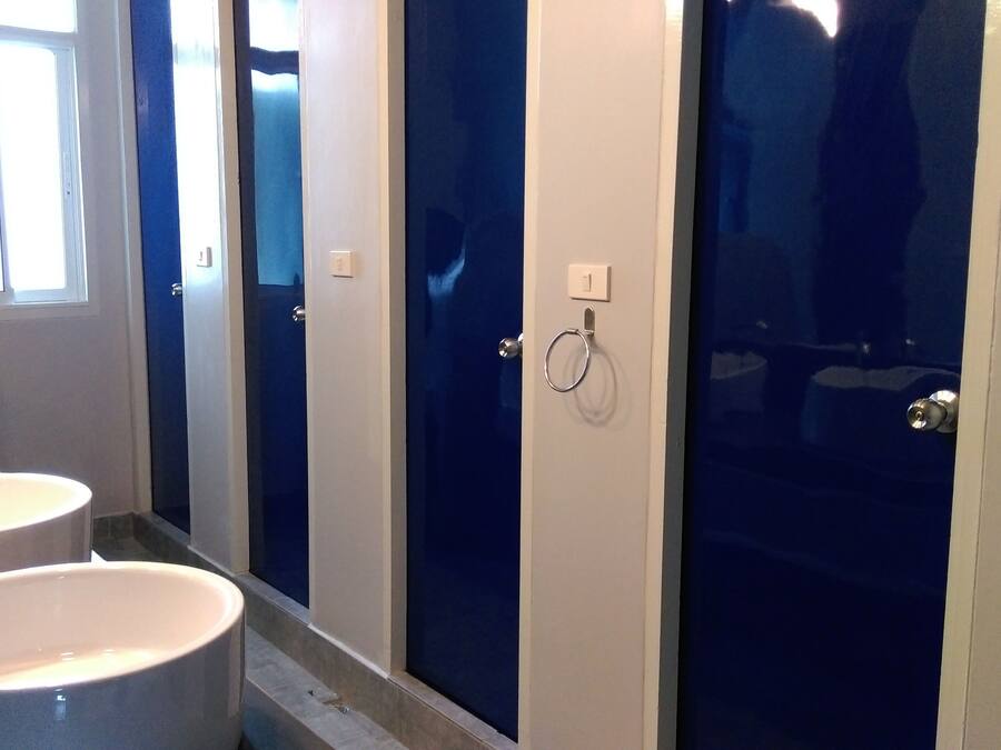 Ein Badezimmer mit drei Waschbecken, einem Spiegel und einer Duschkabine.