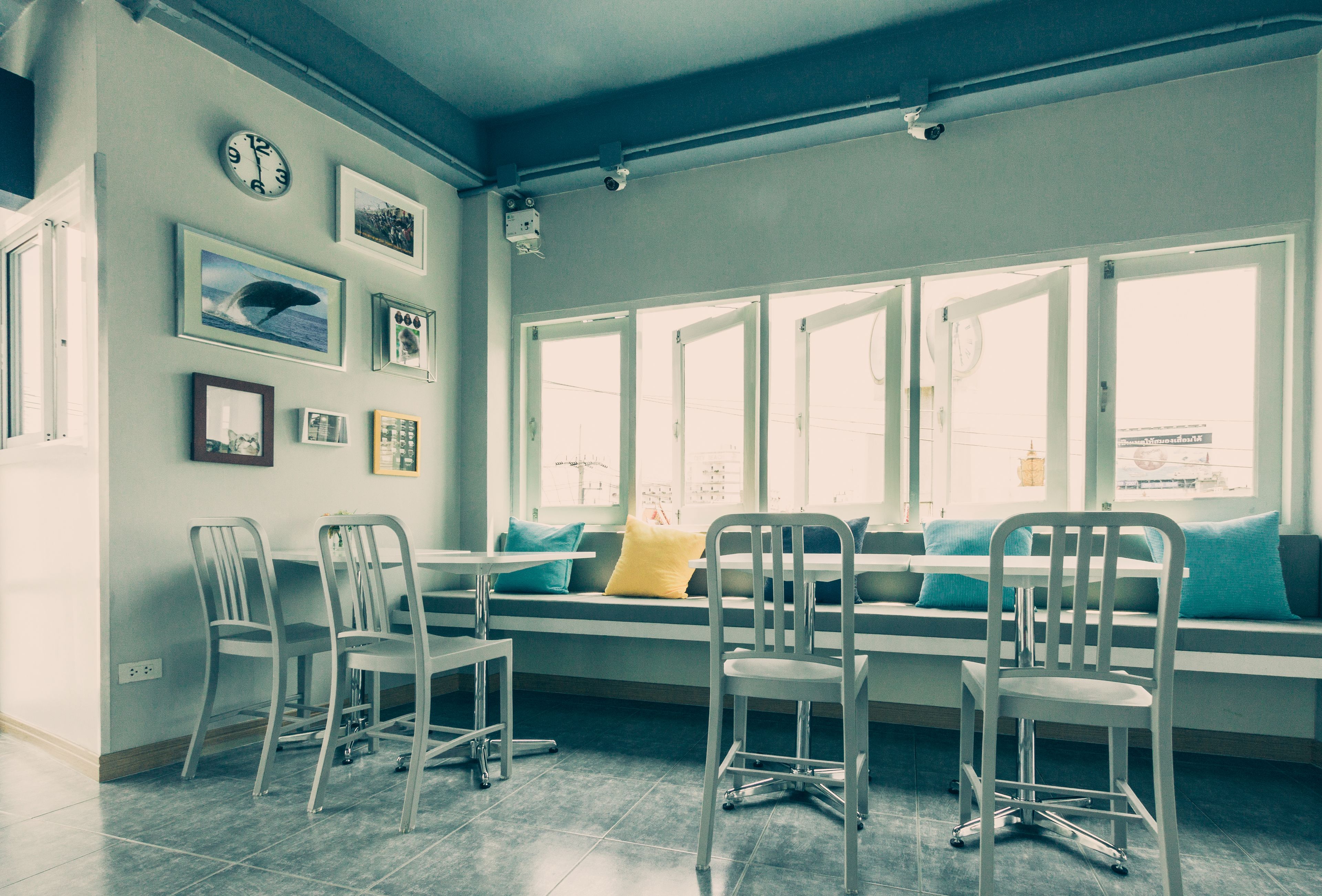 A room with a large window, a sofa with cushions, and several chairs.