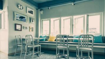 A room with a large window, a sofa with cushions, and several chairs.