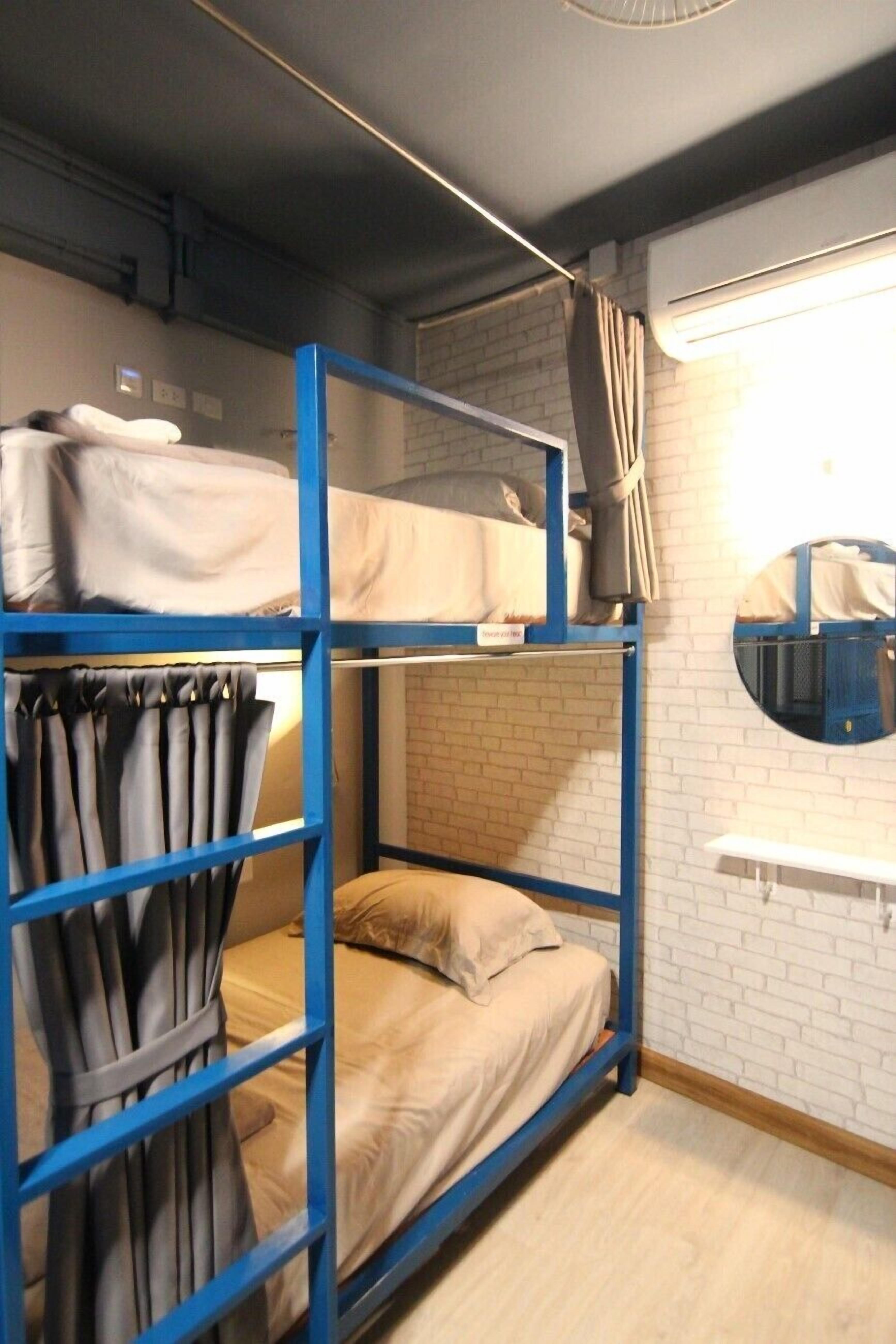 A bunk bed room with a blue frame, a mirror, and a white brick wall.