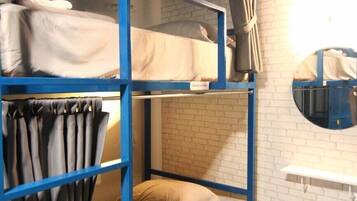 A bunk bed room with a blue frame, a mirror, and a white brick wall.