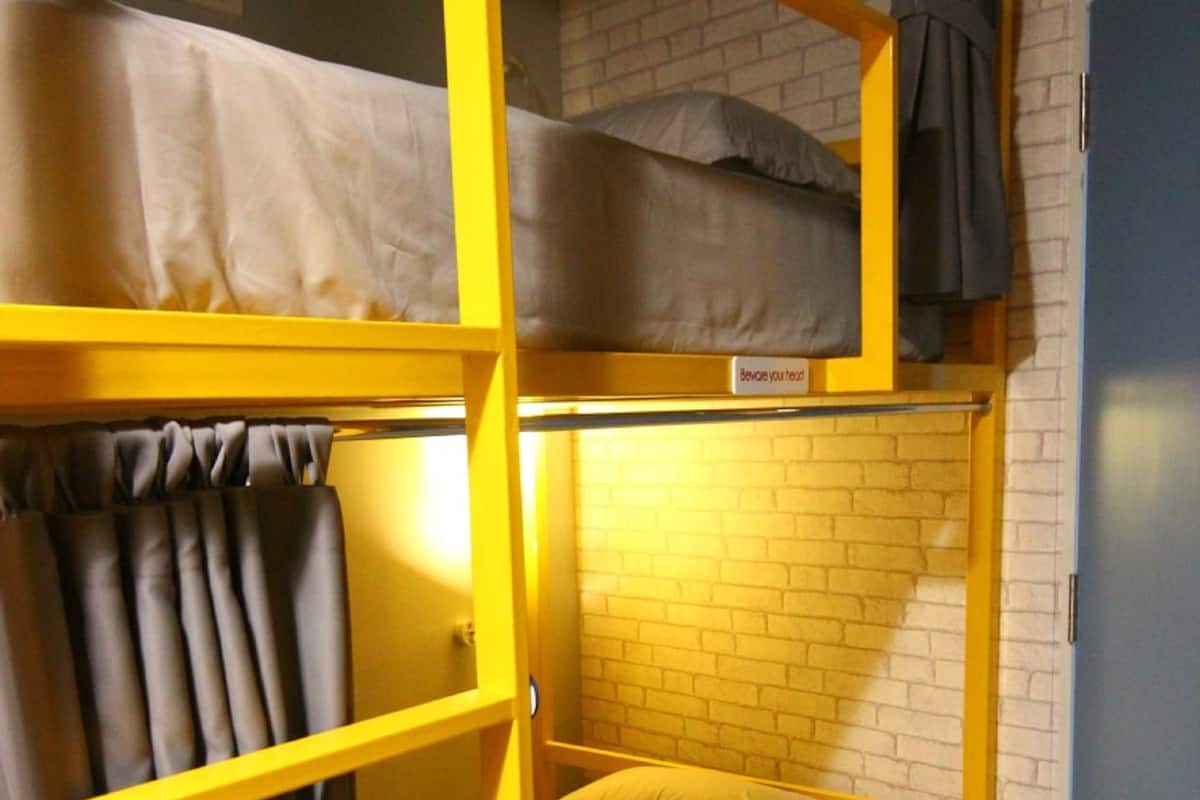 Ein Stockbett mit gelbem Rahmen, einer Matratze und einem Kissen.