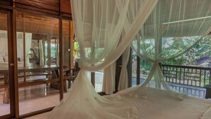 A room with a bed covered in white canopy netting, large windows, and a view of greenery outside. - Sari Bamboo Villas (Ubud)