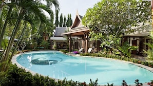 Una piscina rodeada de exuberante vegetación y arquitectura tradicional.