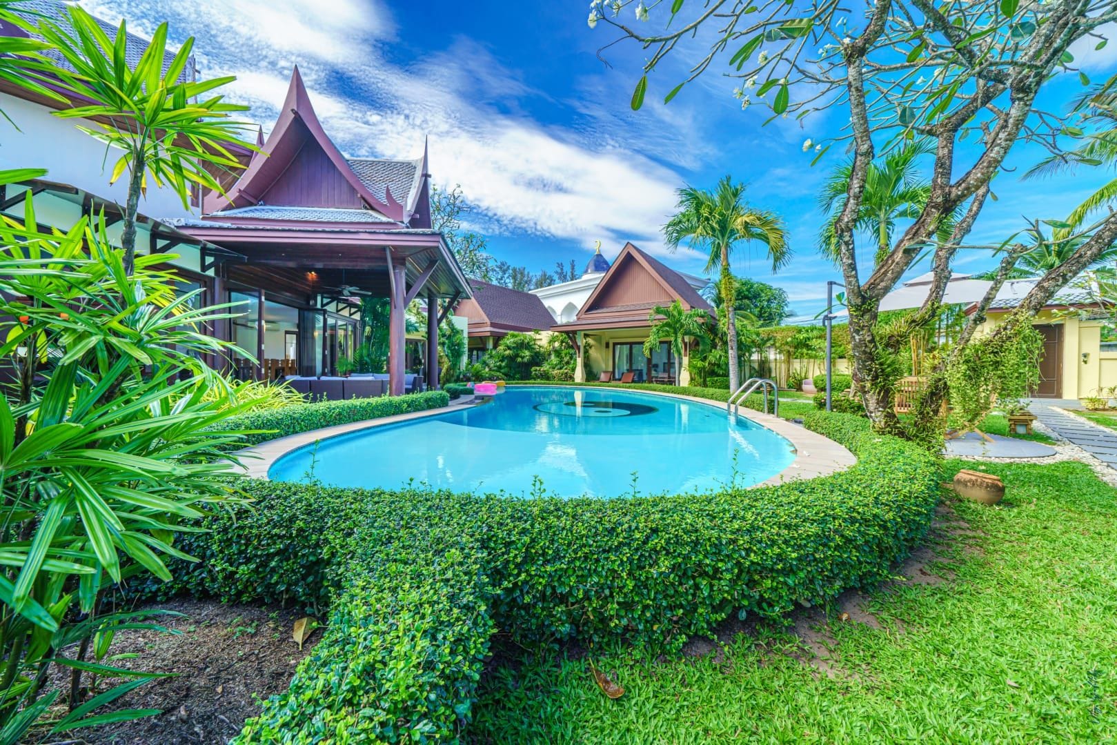 A resort with a swimming pool, covered structures, and lush greenery.