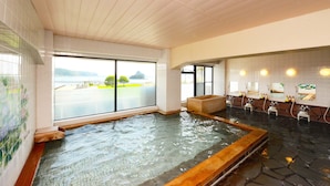 Ein großes Indoor-Whirlpool mit Blick auf einen Parkplatz und Berge durch große Fenster.