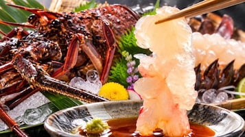 Una bandeja de mariscos con diversos tipos de productos del mar, incluyendo langosta y camarones, servida sobre hielo con salsa para mojar.