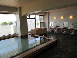 A spa area with a hot tub, a small seating area, and a view of the sea. - Shimoda Ocean Park Hotel (Shimoda)