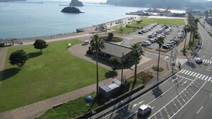 An aerial view of a coastal area with a parking lot, a road, and a body of water.