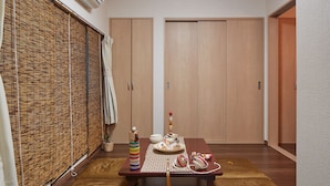 Een kamer met een houten tafel gedekt voor een maaltijd, een bamboe zonwering en een schuifdeur.