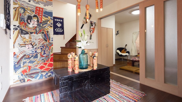 Een traditioneel Japans interieur met een zwarte marmeren toonbank, een kleurrijke wandtapijt en een hanglamp.