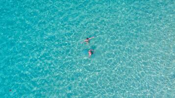 Une piscine d’eau bleue et limpide dans laquelle nagent deux personnes.