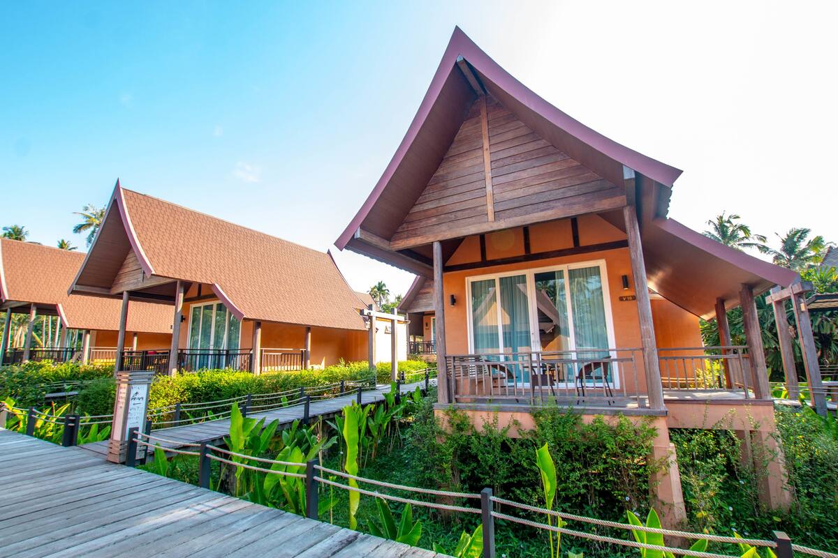 Een resort met houten constructies, een overdekte doorgang en weelderige begroeiing.