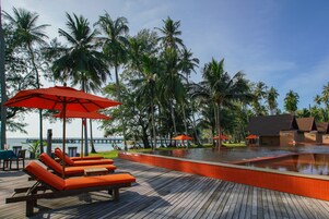Una piscina al aire libre, sillones reclinables de piscina
