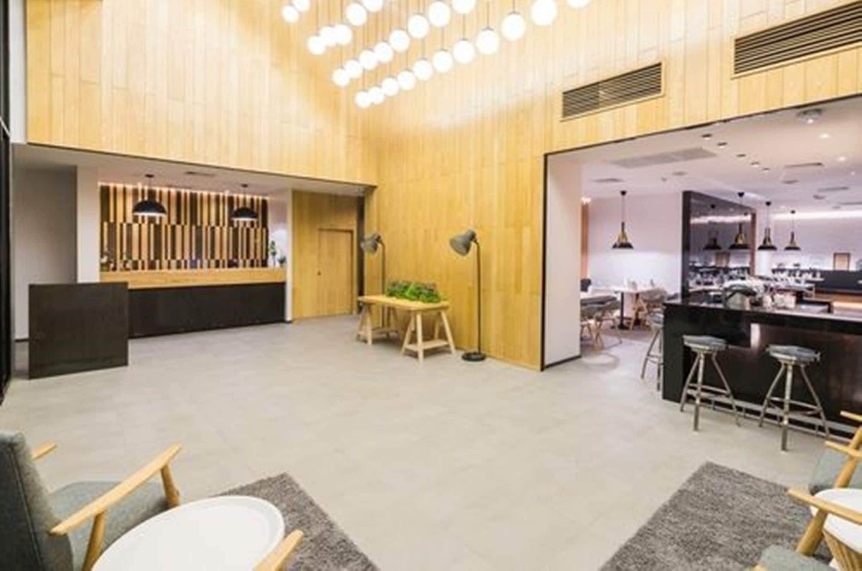 A modern hotel lobby with a reception desk, seating area, and a bar.