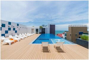 Un área de piscina en la azotea con sillones y vista al mar.