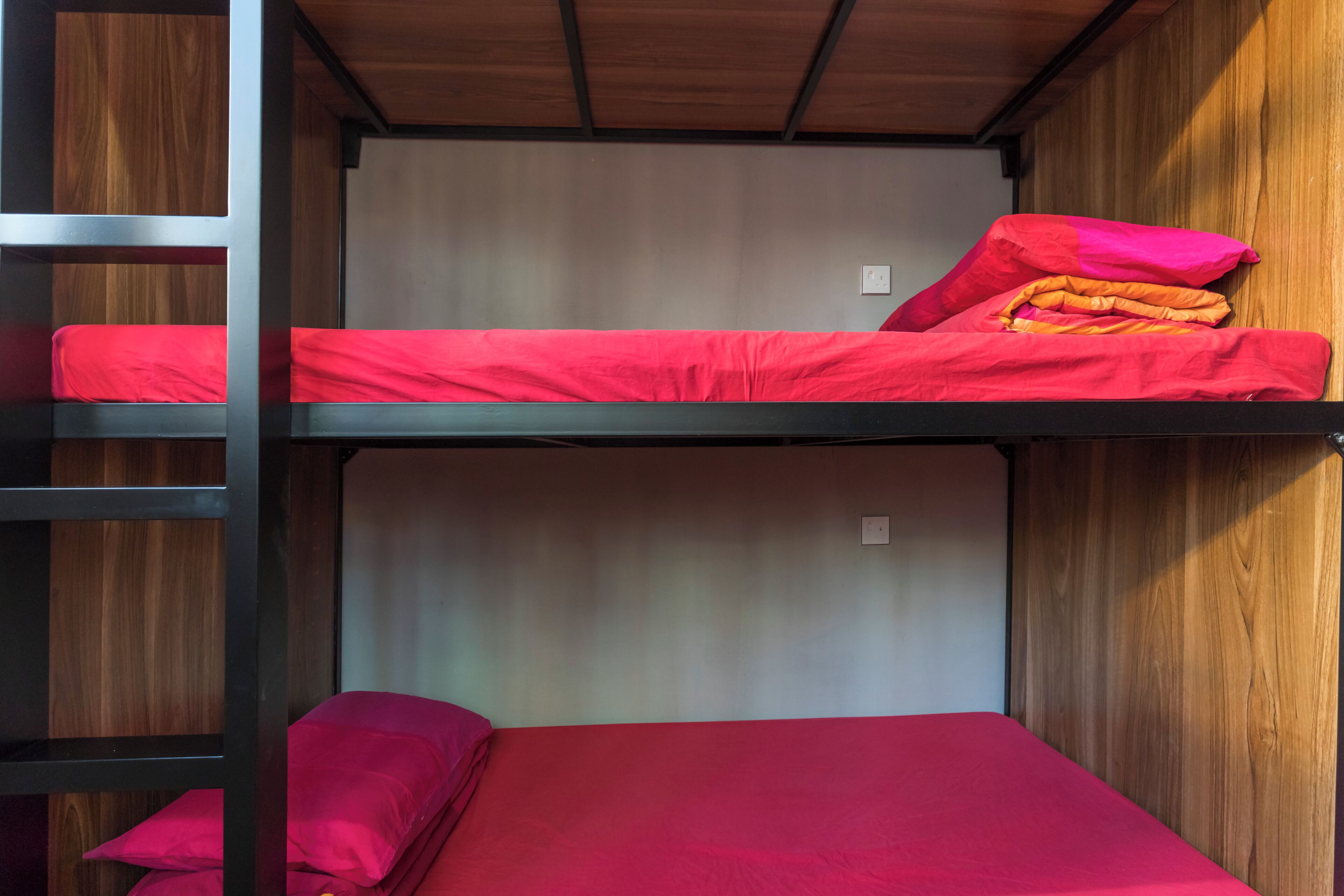 A bunk bed with red bedding and a wooden headboard.