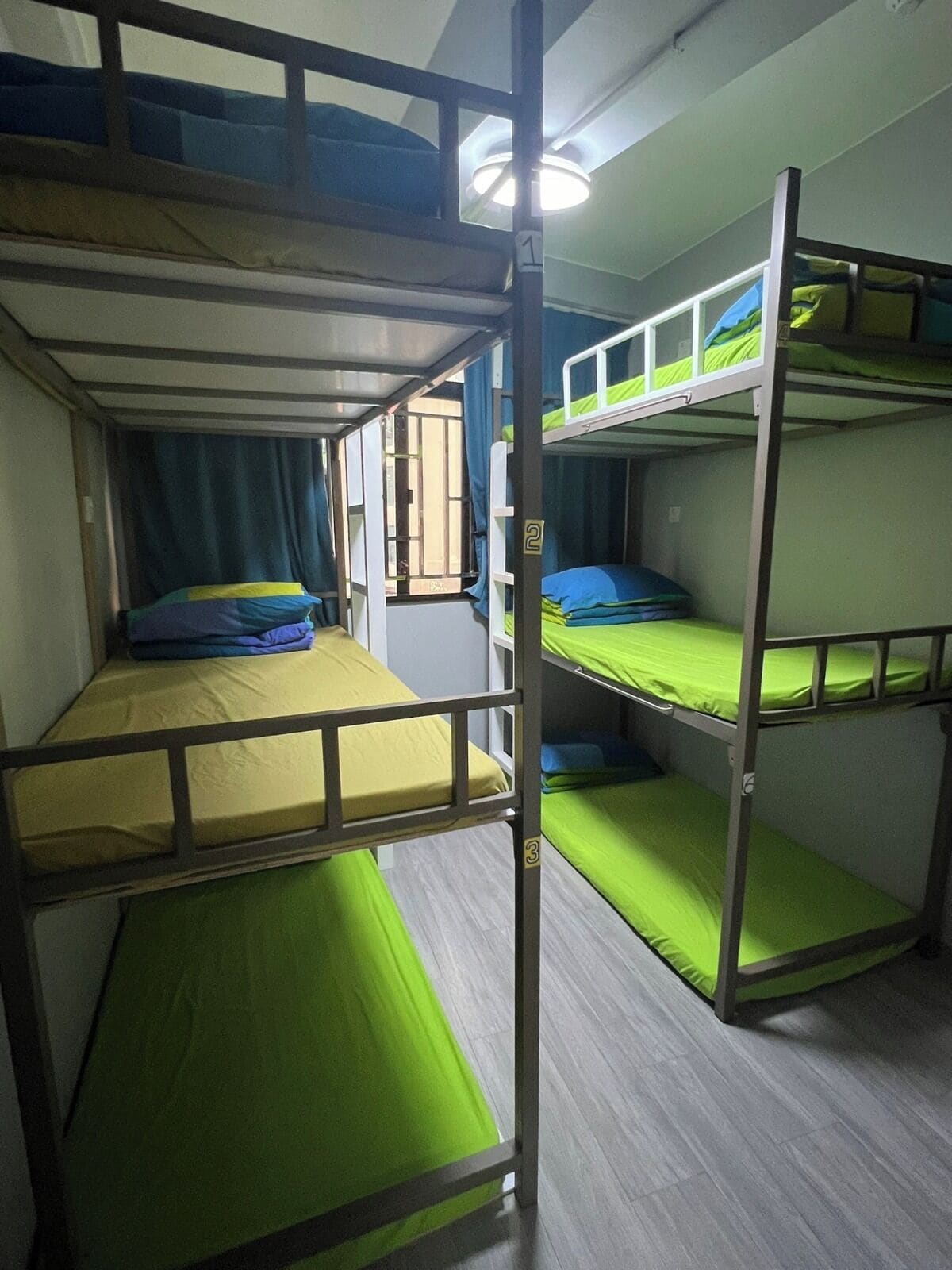 Une chambre avec des lits superposés à trois niveaux, chaque lit étant équipé d’un matelas et d’oreillers.