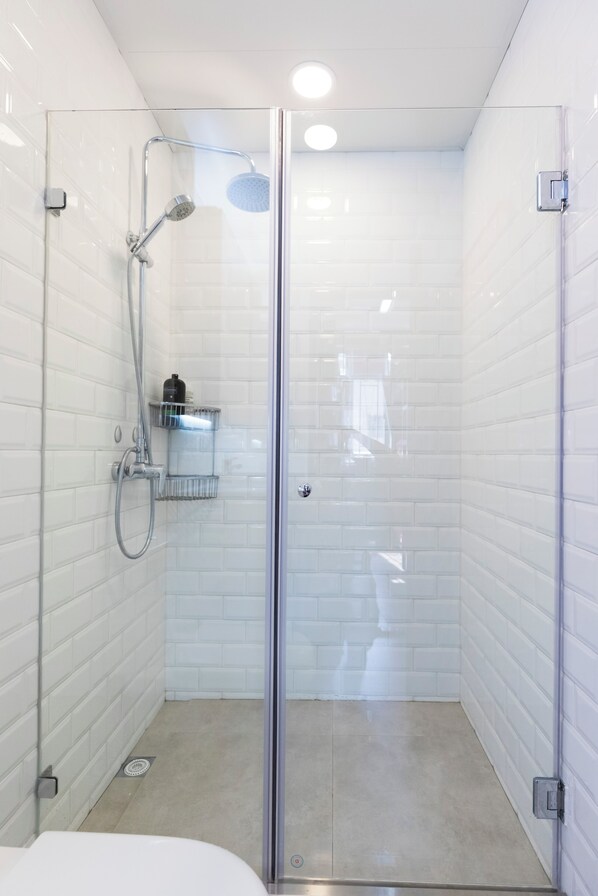 A glass-enclosed shower with white tiled walls and a glass door. - Check Inn HK - Hostel (Hong Kong)