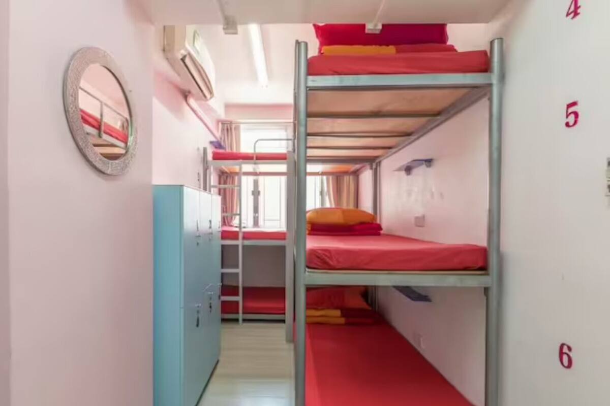 Ein Schlafraum mit Etagenbetten, einem Kleiderschrank und einem Spiegel.