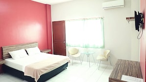 A hotel room with a bed, two chairs, a small table, and an air conditioning unit. - Hotel Fiducia Kaji (Jakarta)