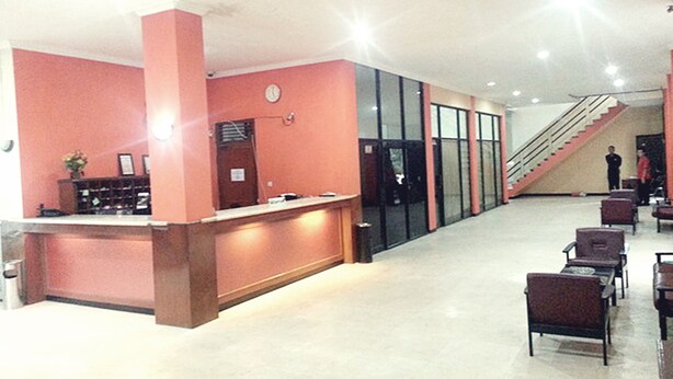 A reception area with a counter, chairs, and a staircase. - Hotel Fiducia Kaji (Jakarta)