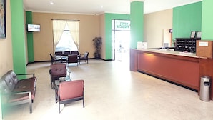 A hotel reception area with a reception desk, seating area with chairs and tables, and a sign indicating the hotel name. - Hotel Fiducia Kaji (Jakarta)