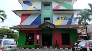 A multi-story building with a colorful facade, a sign reading "HOTEL FIDUCIÀ," and a gated entrance. - Hotel Fiducia Kaji (Jakarta)